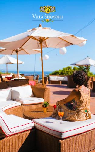 a woman sitting at a table with a wine glass at Hotel Villa Sermolli in Borgo a Buggiano