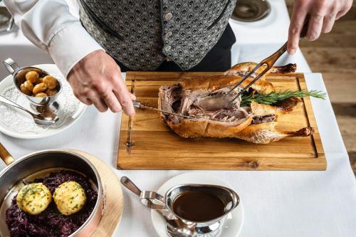 a person cutting a turkey on a cutting board at Hotel Tannbergerhof im Zentrum von Lech in Lech am Arlberg