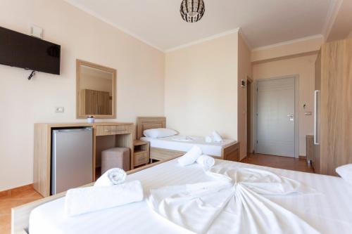 a bedroom with two beds and a tv on the wall at Toni Retzo Rooms in Himare