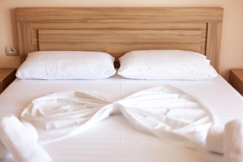 a white bed with a white bow on it at Toni Retzo Rooms in Himare