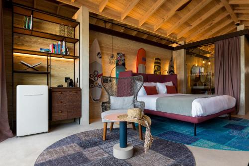 a bedroom with a bed and a chair and a refrigerator at Saba Rock Resort in Virgin Gorda