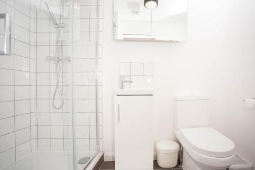 a white bathroom with a toilet and a shower at Brand new one bedroom flat in Central London in London