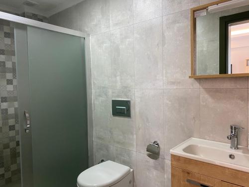 a bathroom with a shower and a toilet and a sink at Kent Otel in Fethiye