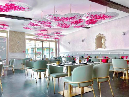 un restaurante con mesas, sillas y sombrillas rosas en Le Sakura, en Morestel