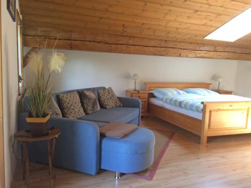 1 dormitorio con sofá azul y cama en Ferienwohnungen Landinger, en Aschau im Chiemgau