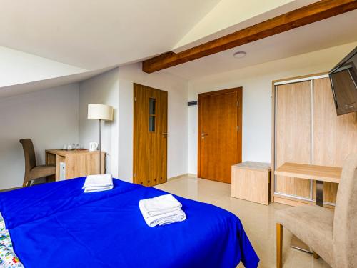 a room with a blue bed with a chair and a tv at Źródło Raduni in Stężyca
