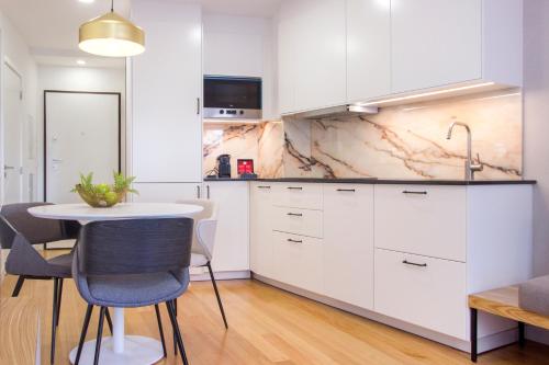 a kitchen with white cabinets and a table with chairs at Santa Luzia Apartments By Guestify in Guimarães