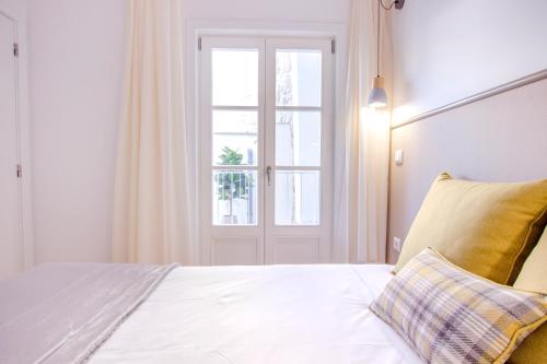 a bedroom with a white bed with a window at Santa Luzia Apartments By Guestify in Guimarães
