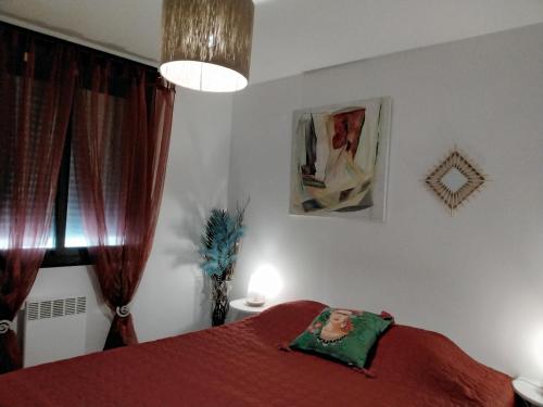 a bedroom with a red bed with a red blanket at Appartement rdc pieds dans l'eau in Sète