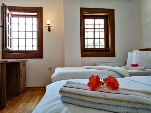 two beds in a room with two red flowers on them at Guest Mansion, Гостински Палат in Rostuša