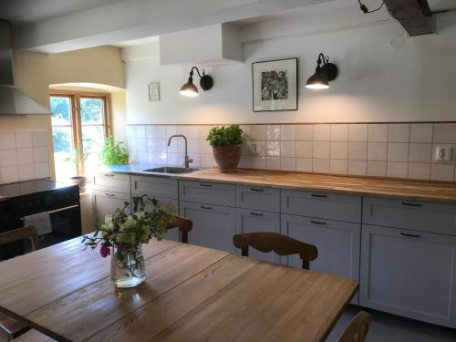 a kitchen with a wooden table with a vase of flowers on it at Österlens bä och bädd in Kivik