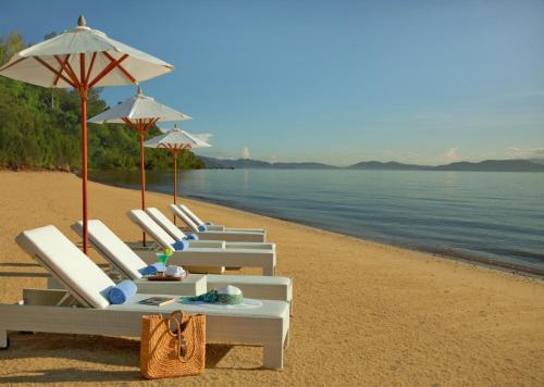a row of lounge chairs and umbrellas on a beach at Gaya Island Resort, Kota Kinabalu - a Small Luxury Hotels of the World in Gaya Island