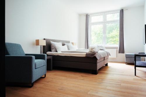 a bedroom with a bed and a chair and a window at Intermar Hotel & Apartments in Glücksburg