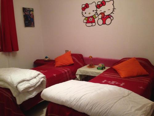 Dos camas en una habitación con hola gatito en la pared en Appartement Nabeul Plage, en Nabeul