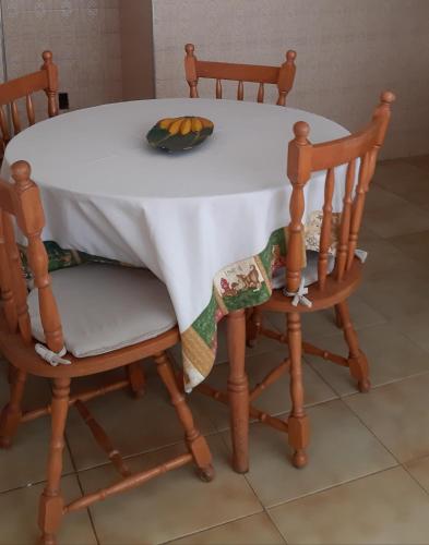 uma mesa branca com duas cadeiras e uma taça de fruta em Apartamento no centro em São Lourenço