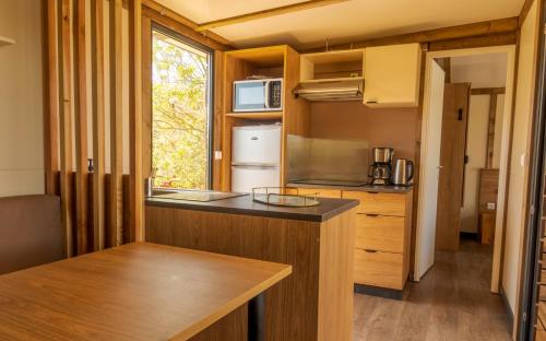 a kitchen with a counter in a tiny house at Camping du Château Vert in Hondainville