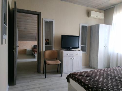 1 dormitorio con 1 cama, TV y silla en Sanpic en Sanzhiyka