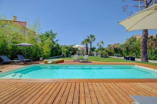 a swimming pool with a wooden deck and an umbrella at Domaine Le Courti - Adult only in Le Barcarès