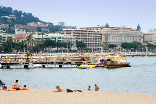 a group of people laying on the beach near a dock at ibis Cannes Mandelieu in Mandelieu-la-Napoule