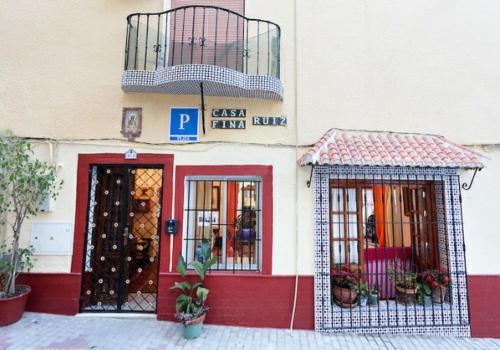 a store with a red and white building with a balcony at Pension casa Fina Ruiz in Almuñécar