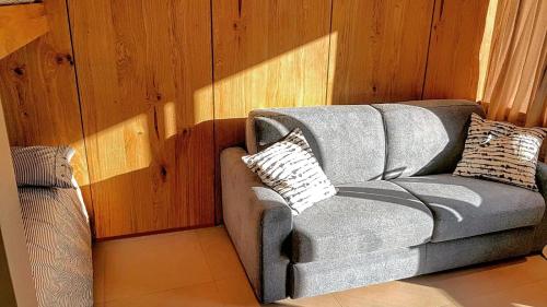 a gray couch in a room with wooden walls at Achillea Alpina Cervinia apartment Vda Vacanze in Vetta CIR 0249 in Breuil-Cervinia