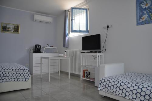 a white room with two beds and a television at La Casa Dei Nonni in Felegara