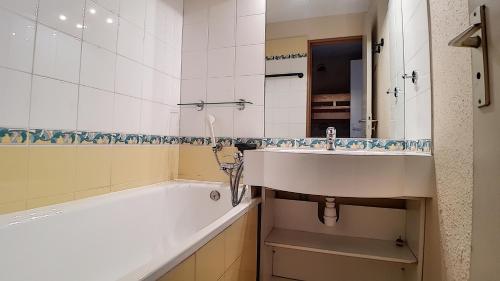 un baño con lavabo y bañera en travelski home classic - Résidence Boedette, en Les Menuires