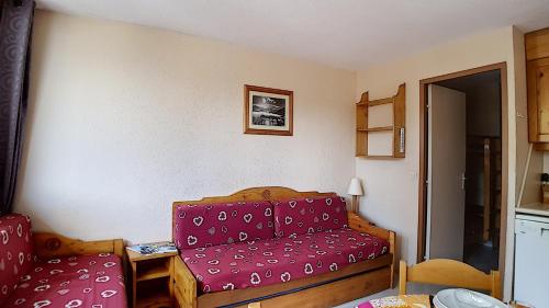 Cette chambre comprend un canapé rouge et une chaise. dans l'établissement travelski home classic - Résidence Boedette, aux Menuires