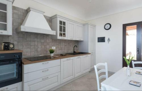 a kitchen with white cabinets and a sink and a table at Camilla suite in Siracusa