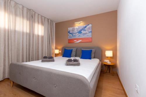 een slaapkamer met een groot bed met blauwe kussens bij Yumbo Teror Two Bedroom Apartment in Playa del Inglés