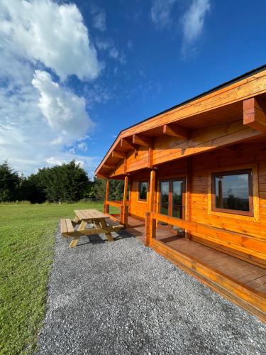 uma cabana de madeira com uma mesa de piquenique ao lado em Southern County Resort em Sheean