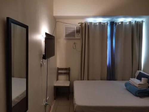 1 dormitorio con cama, espejo y ventana en Mack's Awesome Place 24 with Netflix and FastUnliwifi en Manila