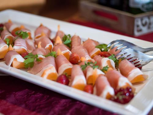 a plate of food with fruit and a fork on it at Hotel Landhaus Zillertal in Fügen