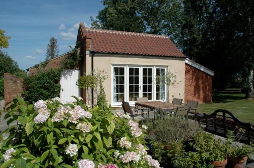 Field Cottage Bed and Continental Breakfast في East Harling: منزل صغير مع طاولة وكراسي وزهور