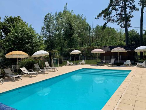- une piscine avec des chaises longues et des parasols dans l'établissement Le Moulin Du Port, à Saint-Georges-sur-Cher