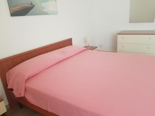 a bedroom with a pink bed with a wooden headboard at B&B La pineta in Quasani