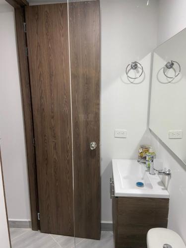 a bathroom with a wooden door and a sink at Aparta estudio Amoblado Sabaneta Colombia. Moderno, céntrico y cómodo. in Sabaneta