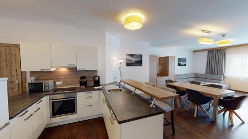 a kitchen with white cabinets and a table and a dining room at A Casa Saphir Appartement-Hotel in Sölden