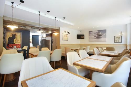 een eetkamer met tafels en witte stoelen bij Hotel Le Chat Noir in Parijs