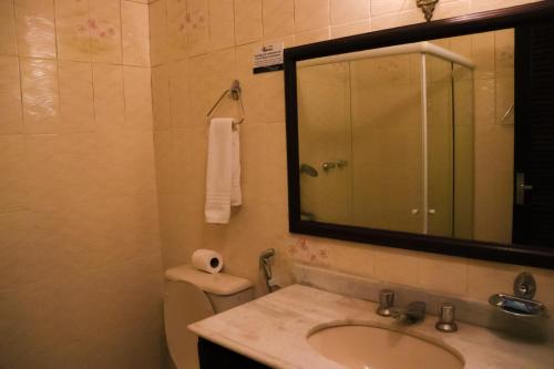 y baño con lavabo, espejo y aseo. en Hotel Itamaracá, en Miguel Pereira