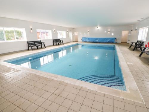 a large swimming pool with blue water in a building at Rowan Lodge in Oakham