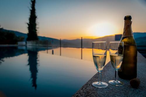 a bottle of champagne and two glasses next to a pool at Golden Mirror in Lamego