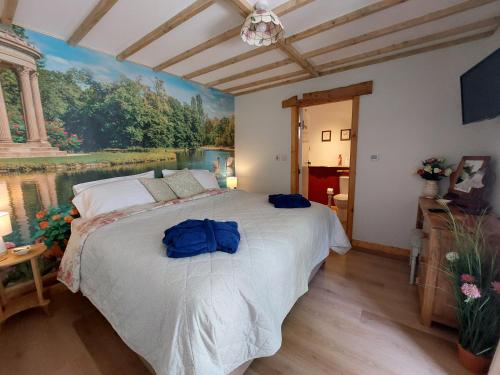 a bedroom with a large bed with a painting on the wall at Wesley House Holidays - Choice of 2 Quirky Cottages in 4 private acres in Redruth
