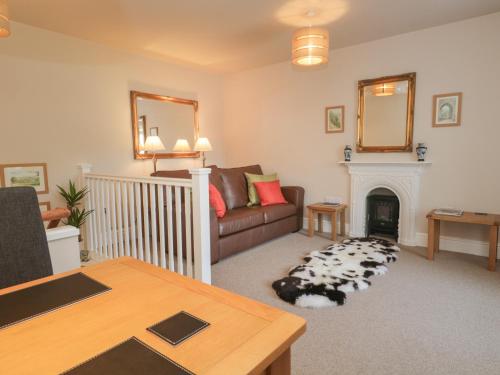 uma sala de estar com um sofá e uma lareira em Crag End Cottage em Grange Over Sands