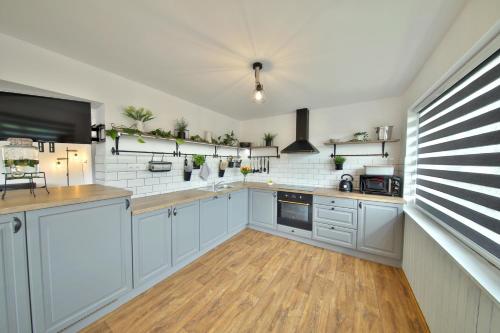 a large kitchen with white cabinets and wooden floors at Chata Malá Skála v Českém ráji in Malá Skála