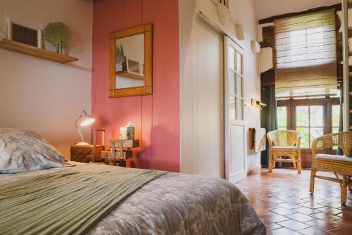 1 dormitorio con paredes rosas, 1 cama y 1 mesa en La douce France en Collonges