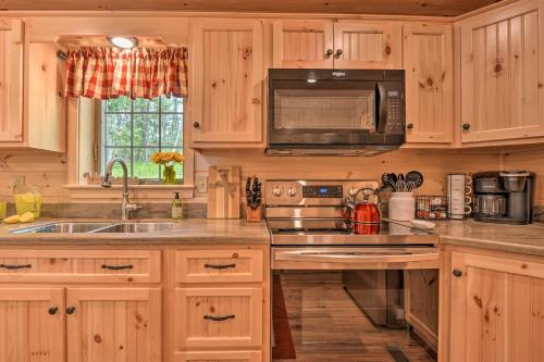 a kitchen with wooden cabinets and a sink and a microwave at Secluded Mountain Cabin in Wardensville! in Wardensville