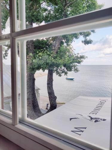 una ventana con vistas a un árbol y al océano en BoHouse apartment No2, en Preila