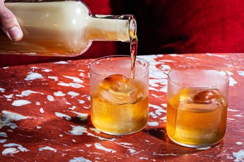 a drink being poured into two glasses on a table at Riggs Washington DC in Washington