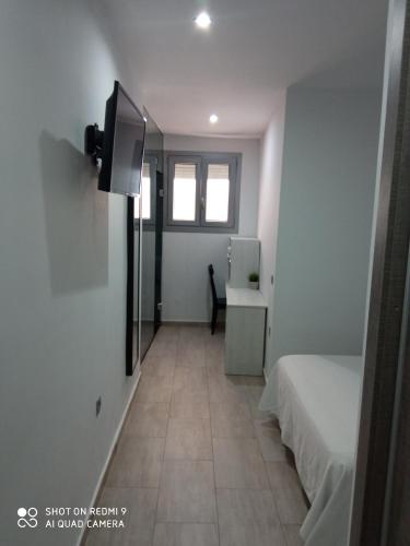 a room with a bed and a desk and a tv at Hostal Campito in Conil de la Frontera